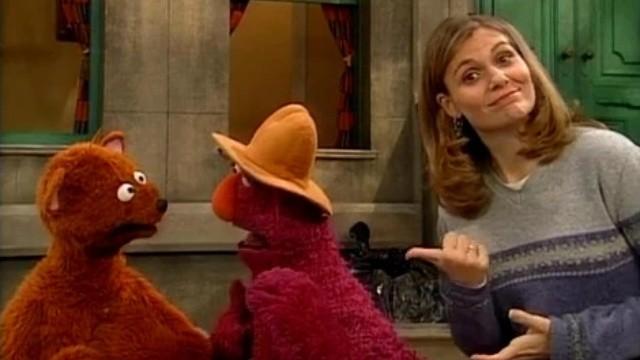 Telly and Baby Bear take turns wearing Papa Bear's hat